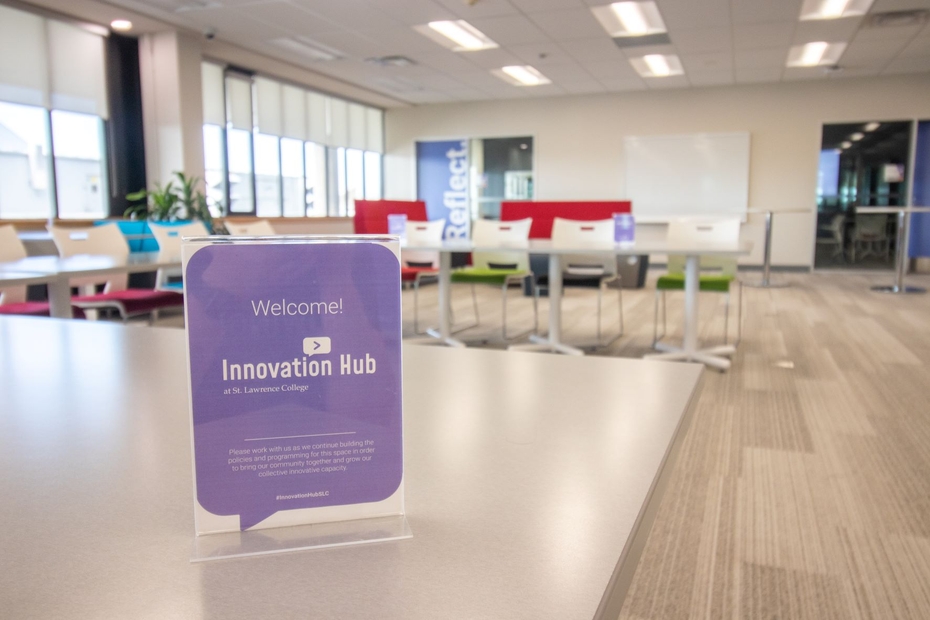 A welcome to the Innovation Hub sign is on a table, with tables an chairs in the Innovation Hub space in the background.
